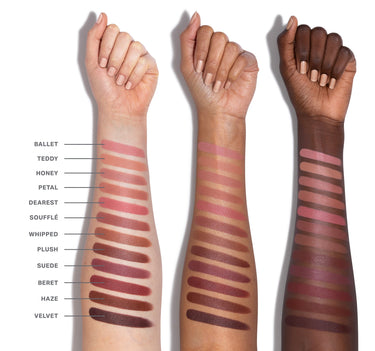 Three arms with different skin tones displaying a range of lipstick swatches on a white background.